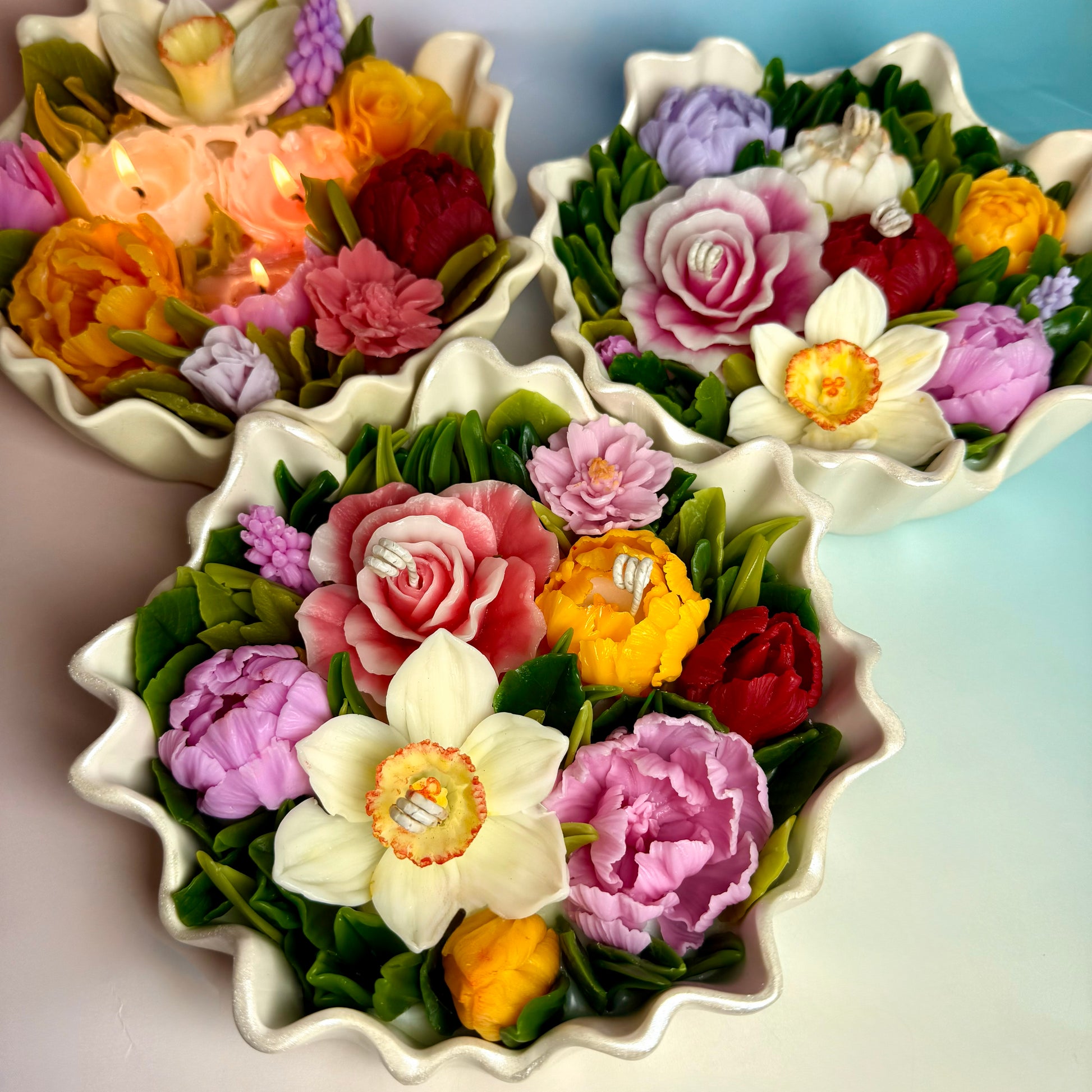 Display of three large floral centrepiece candles featuring vibrant multi-coloured wax blooms