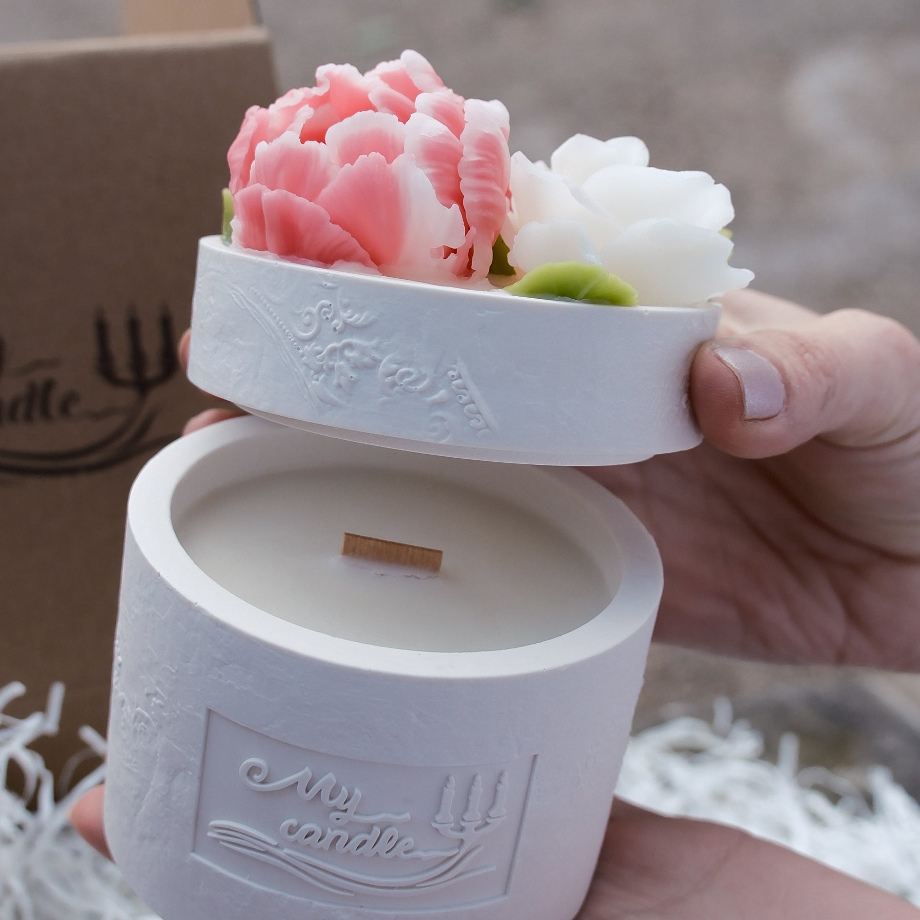 Main photo showing the 2-part candle with a beeswax rose, ranunculus, and tulip lid being lifted from the base.
