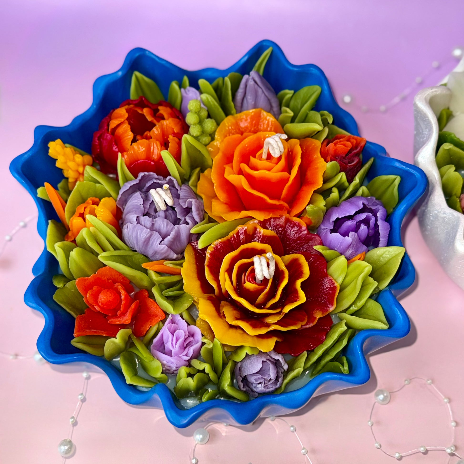 Top down view of intricate orange roses and purple tulips made from premium beeswax.